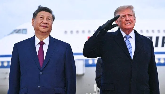 Xi Jinping standing beside Donald Trump, who wears black gloves and salutes in front of an aircraft