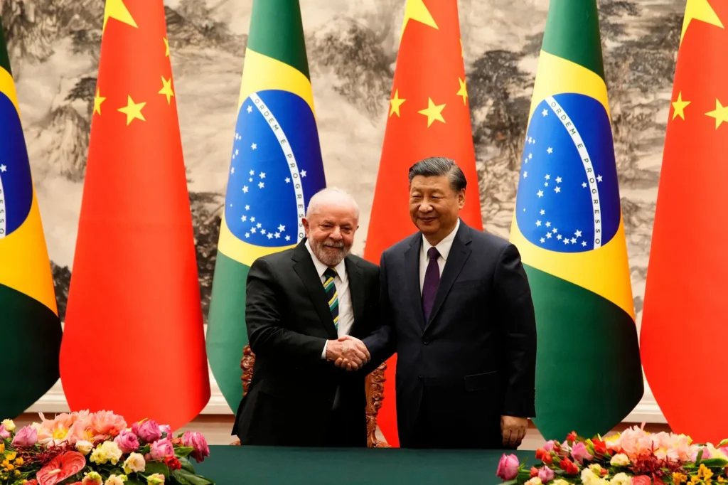 Luiz Inácio Lula da Silva and Xi Jinping shake hands in front of Brazilian and Chinese flags