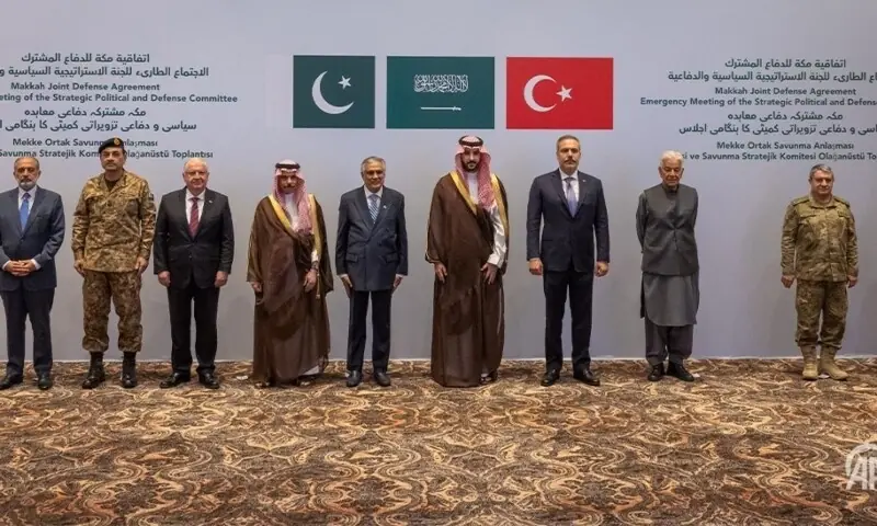 Delegates standing in front of Pakistani, Saudi, and Turkish flags at a Makkah Joint Defense Agreement meeting