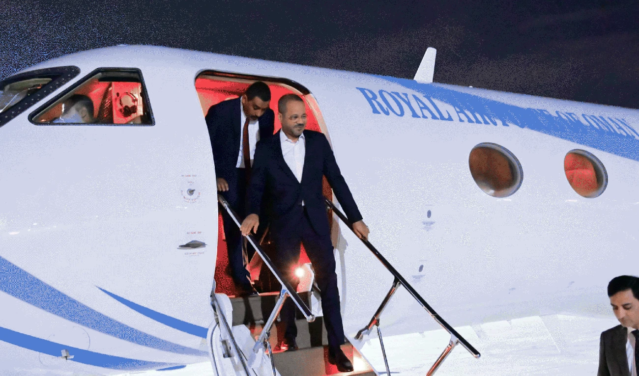 Man in a suit disembarking from a Royal Air Force of Oman airplane at night