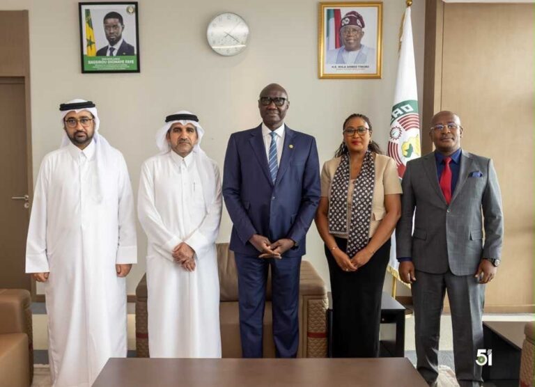 Five officials, including two in traditional Arab attire and three in business suits, standing together in an office