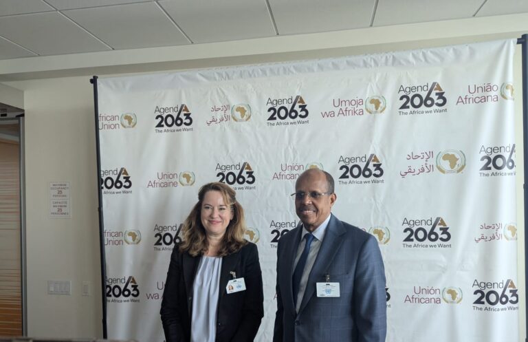 A woman and a man standing in front of an African Union Agenda 2063 backdrop