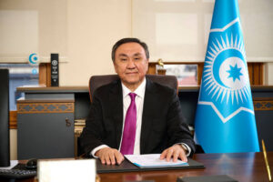 Kubanychbek Omuraliev seated at his desk next to the Organization of Turkic States flag