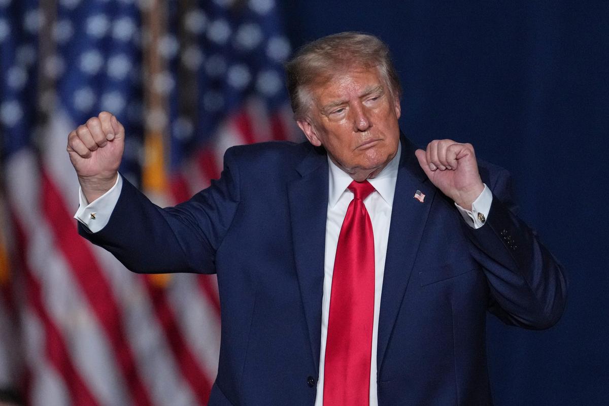 Donald Trump raises his fists in a dancing gesture in front of American flags