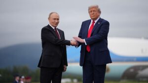 Vladimir Putin and Donald Trump shaking hands outdoors in front of an aircraft