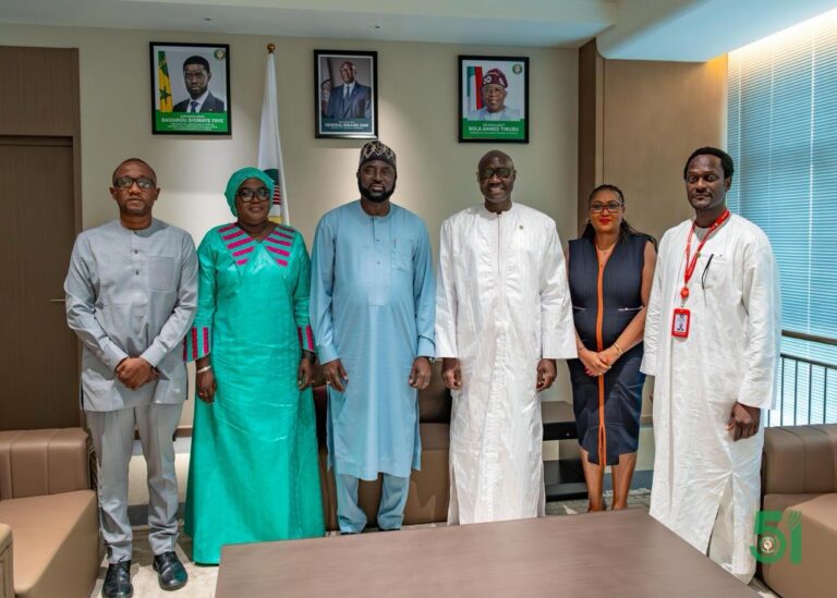 Six people posing in an office beneath framed portraits of West African leaders