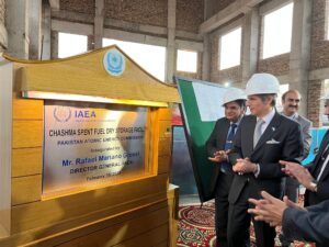Rafael Mariano Grossi clapping beside the inauguration plaque for the Chashma Spent Fuel Dry Storage Facility