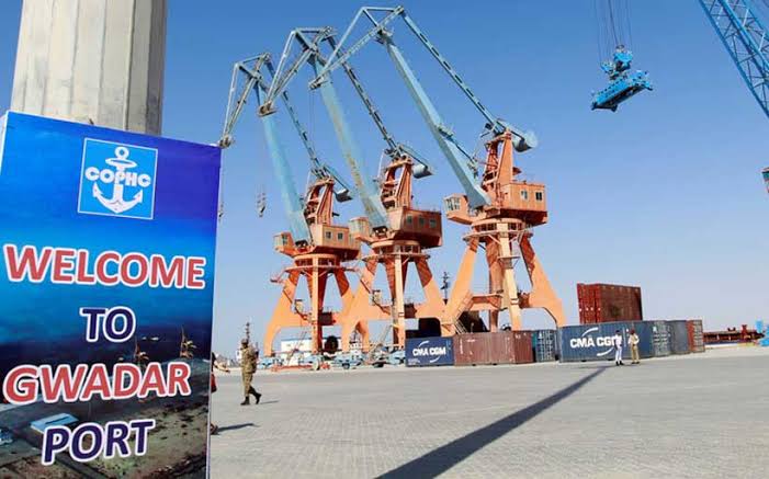 Sign reading Welcome to Gwadar Port with large orange cranes and shipping containers in the background