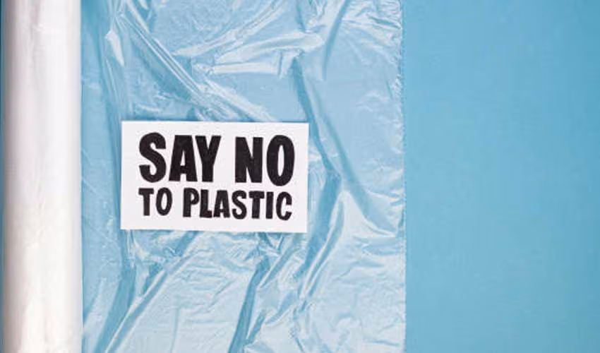 Card reading Say No To Plastic on clear plastic wrap over a blue background