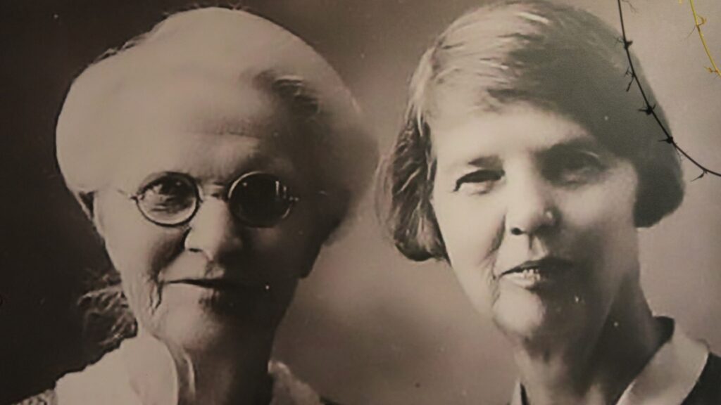 An older woman with round eyeglasses and white hair posing next to a younger woman with short bobbed hair