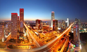 Beijing skyline at dusk featuring illuminated modern skyscrapers and light trails on busy highway interchanges