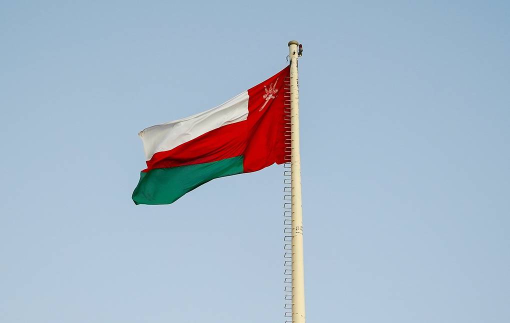 Flag of Oman waving on a flagpole against a clear sky