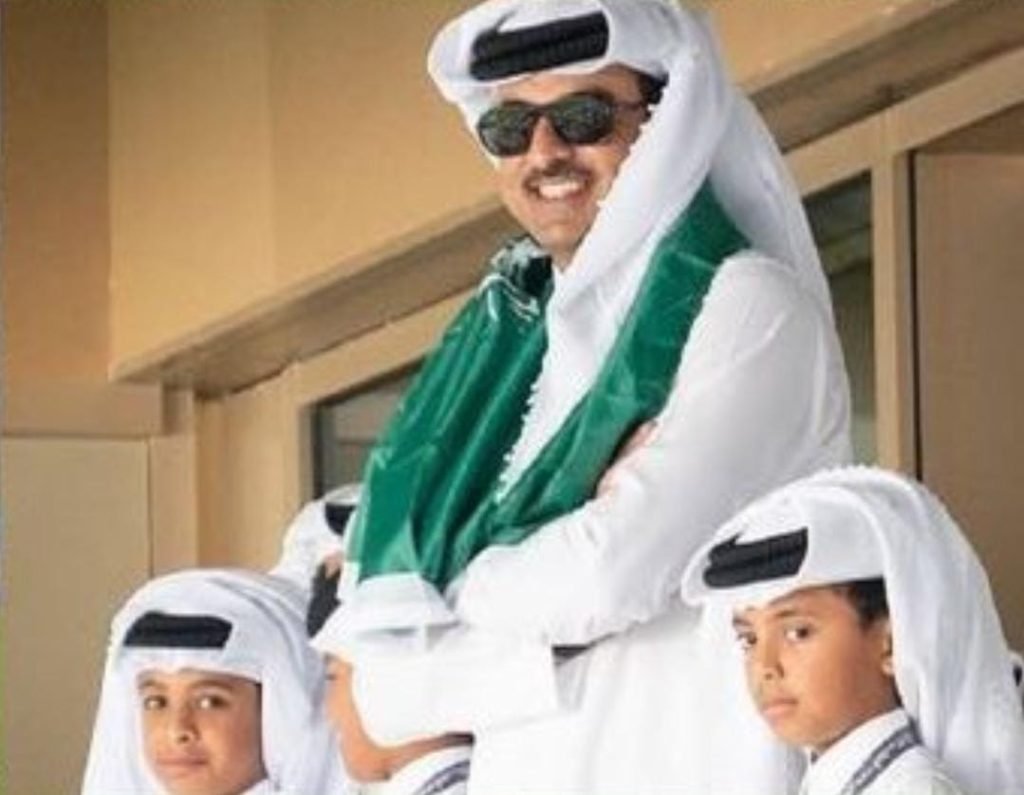 Emir of Qatar wearing the Saudi flag around his neck.