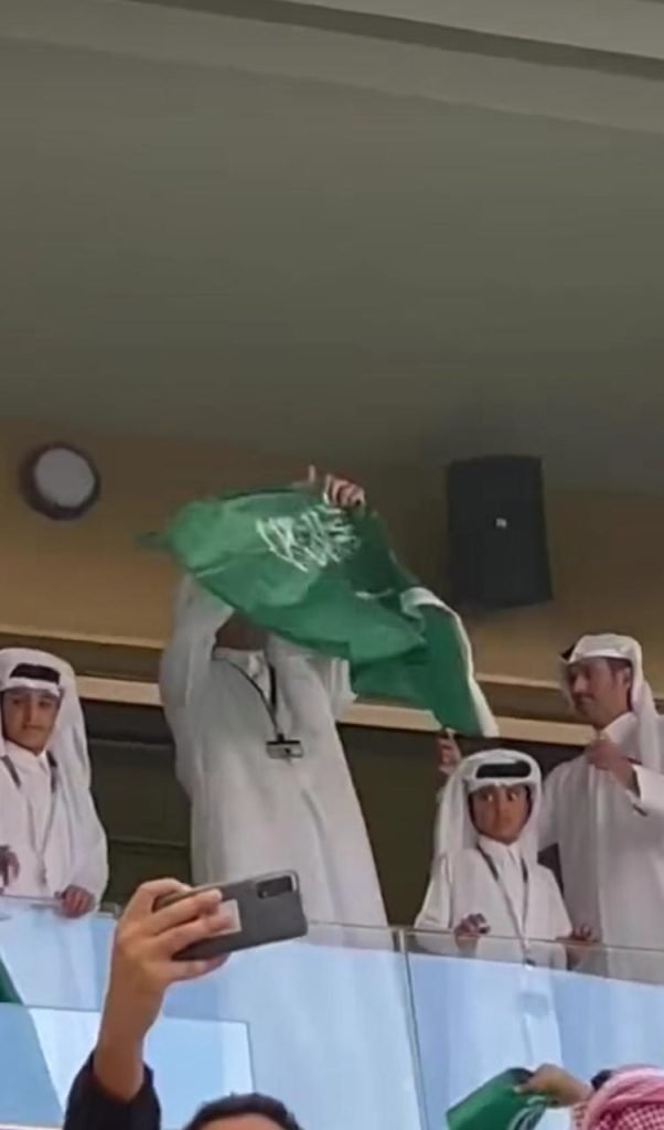 Qatar's Emir wearing the Saudi flag around his neck.