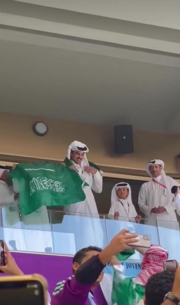 Qatar's Emir wearing the Saudi flag around his neck.