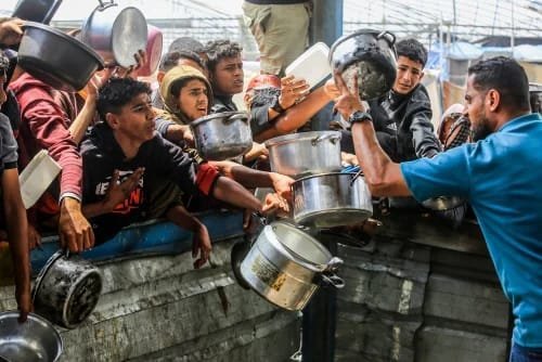 Children wait at a meal distribution stand in Al-Mawasi area of Khan Yunis, Southern GAZA, on May 12, 2025.