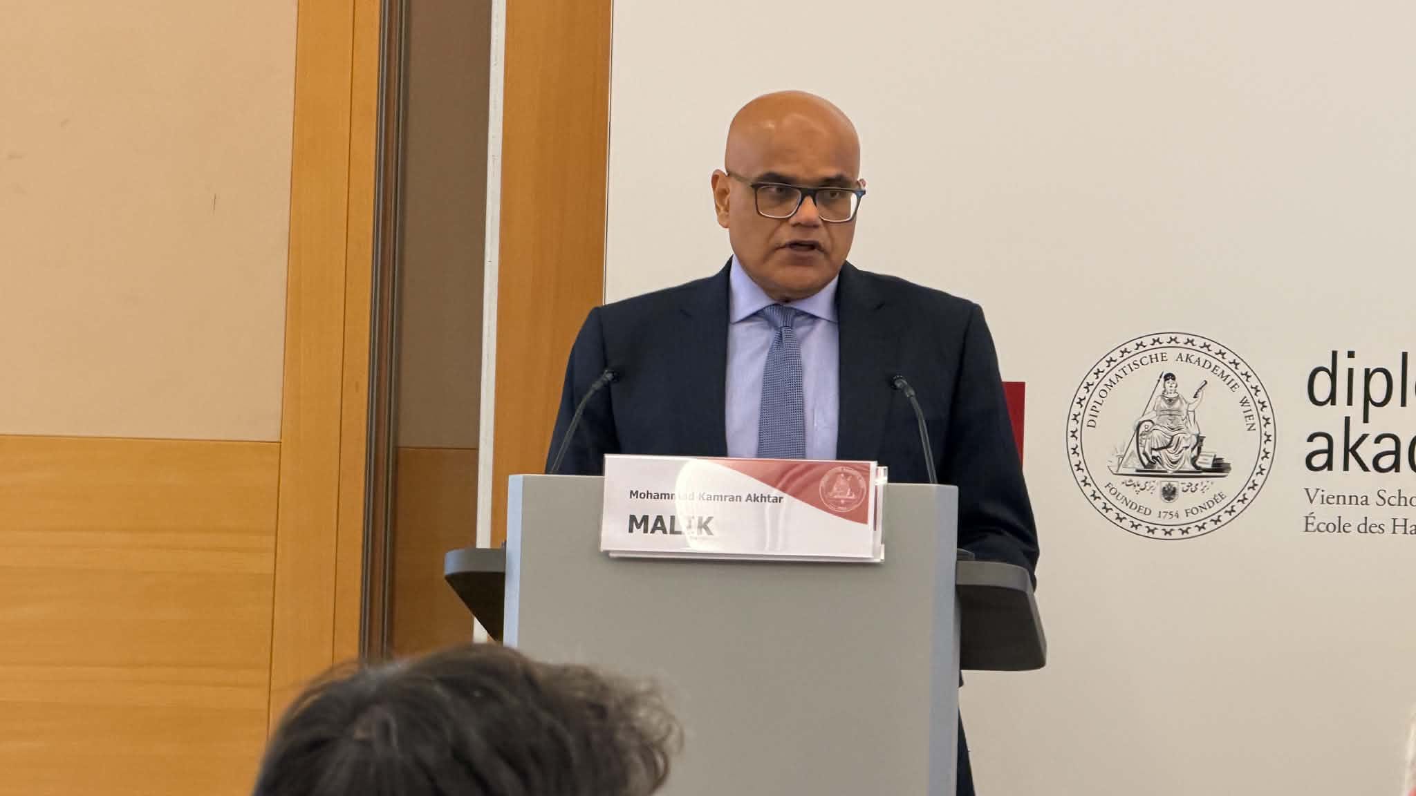 Mohammad Kamran Akhtar speaking at a podium at the Diplomatische Akademie Wien