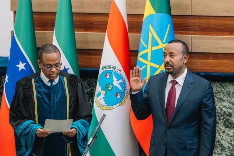 Abiy Ahmed raises his right hand to take an oath of office while an official in ceremonial robes reads from a paper