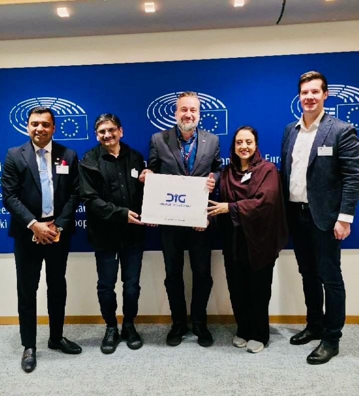 Five people standing in front of a European Parliament backdrop, holding a DIG bag