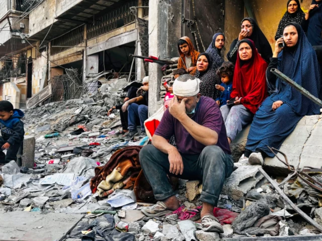 An injured man sits on the rubble of a building destroyed by an Israeli strike in Beit Lahia, Gaza